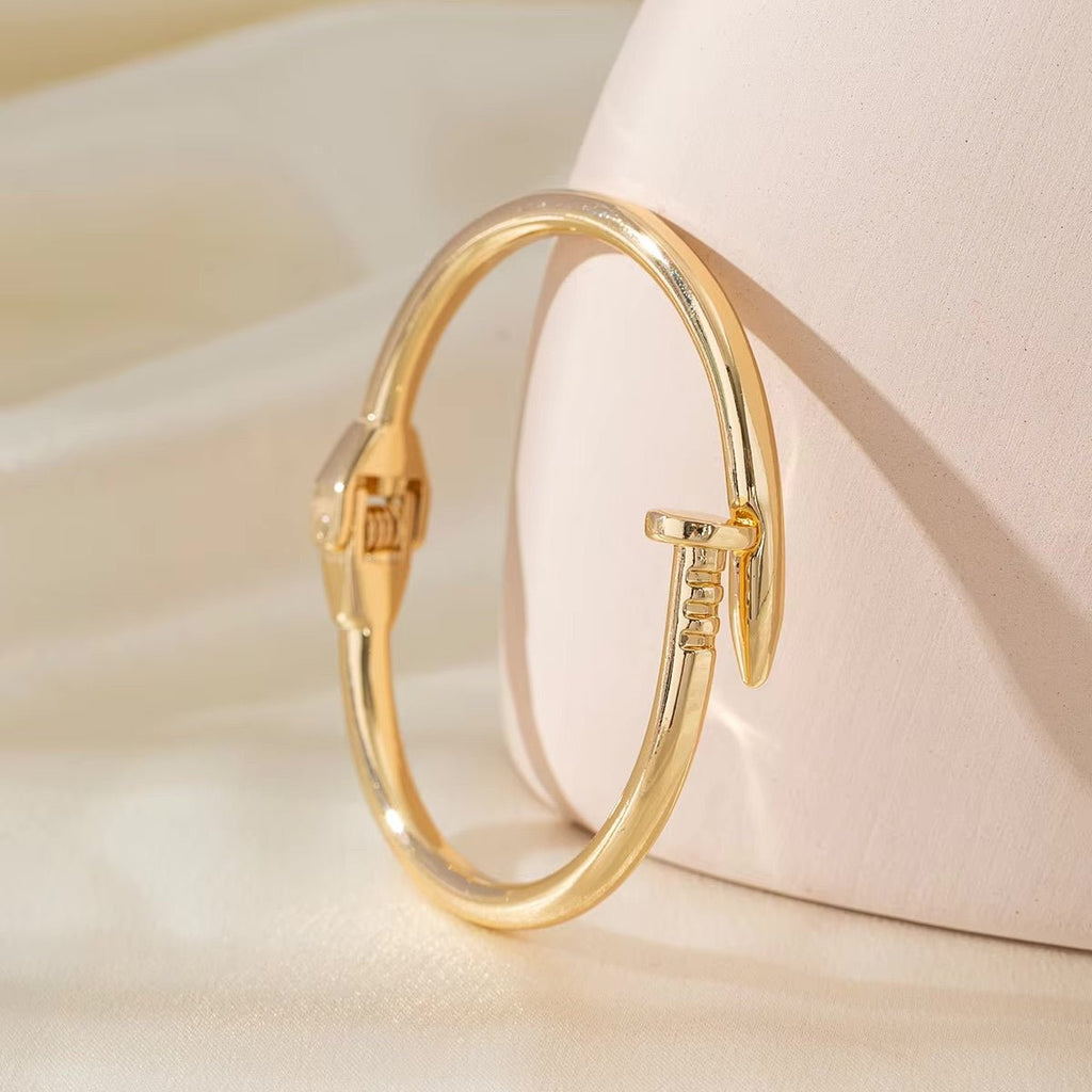 Bracelet jonc en acier inoxydable doré, design clou minimaliste et élégant pour femme.