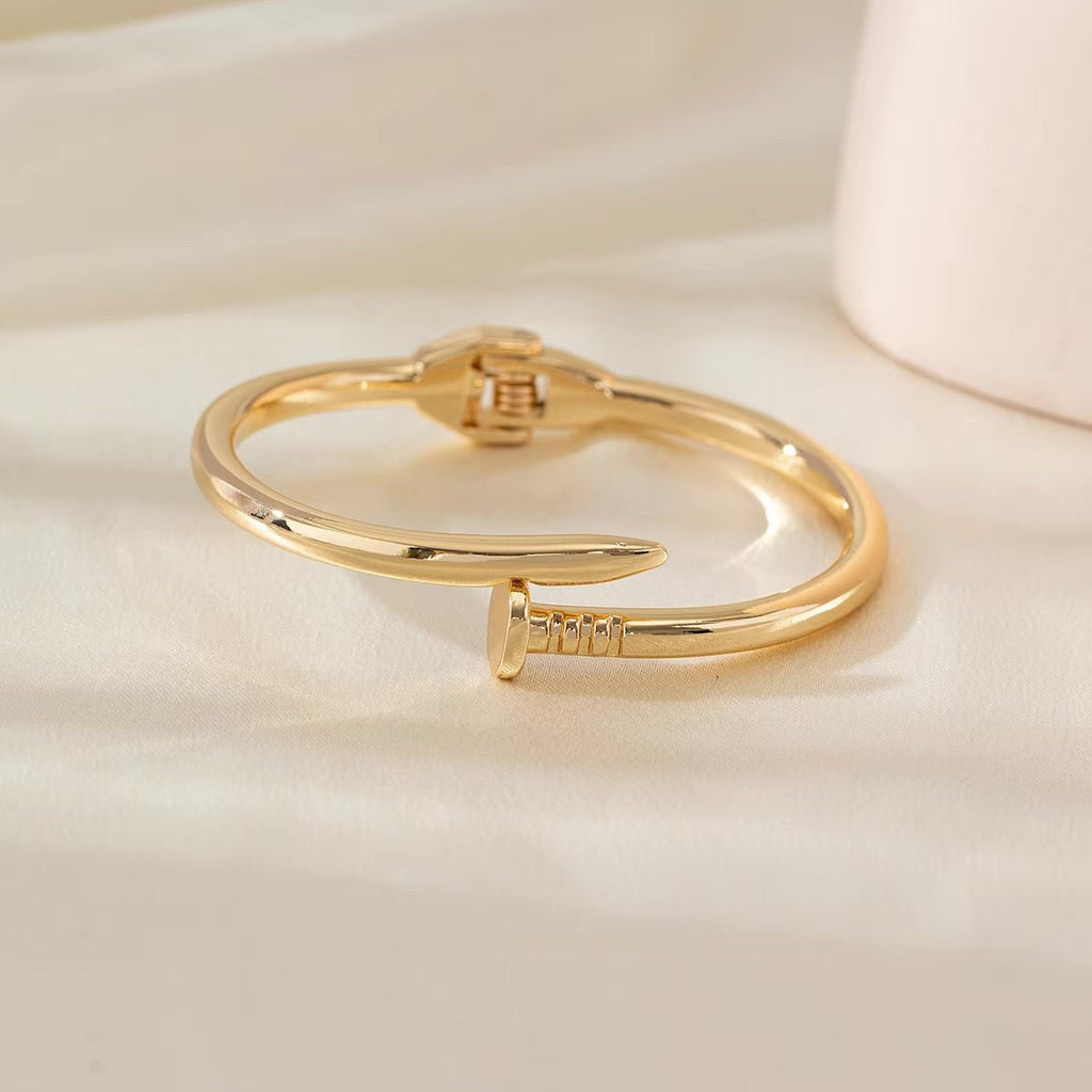 Bracelet jonc en acier inoxydable doré avec design clou minimaliste pour femme.