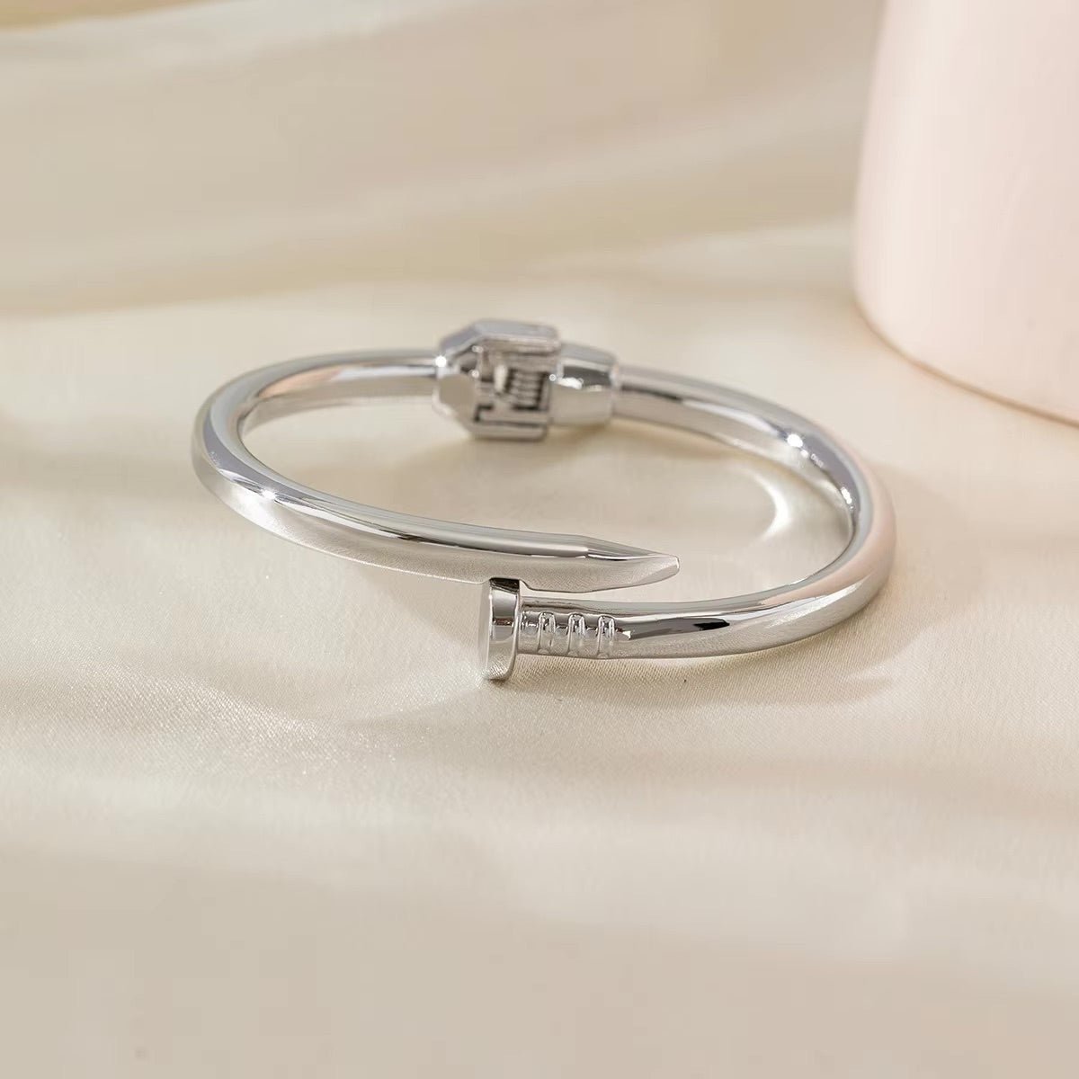 Bracelet jonc argenté en acier inoxydable avec embouts en forme de clou finition brillante.