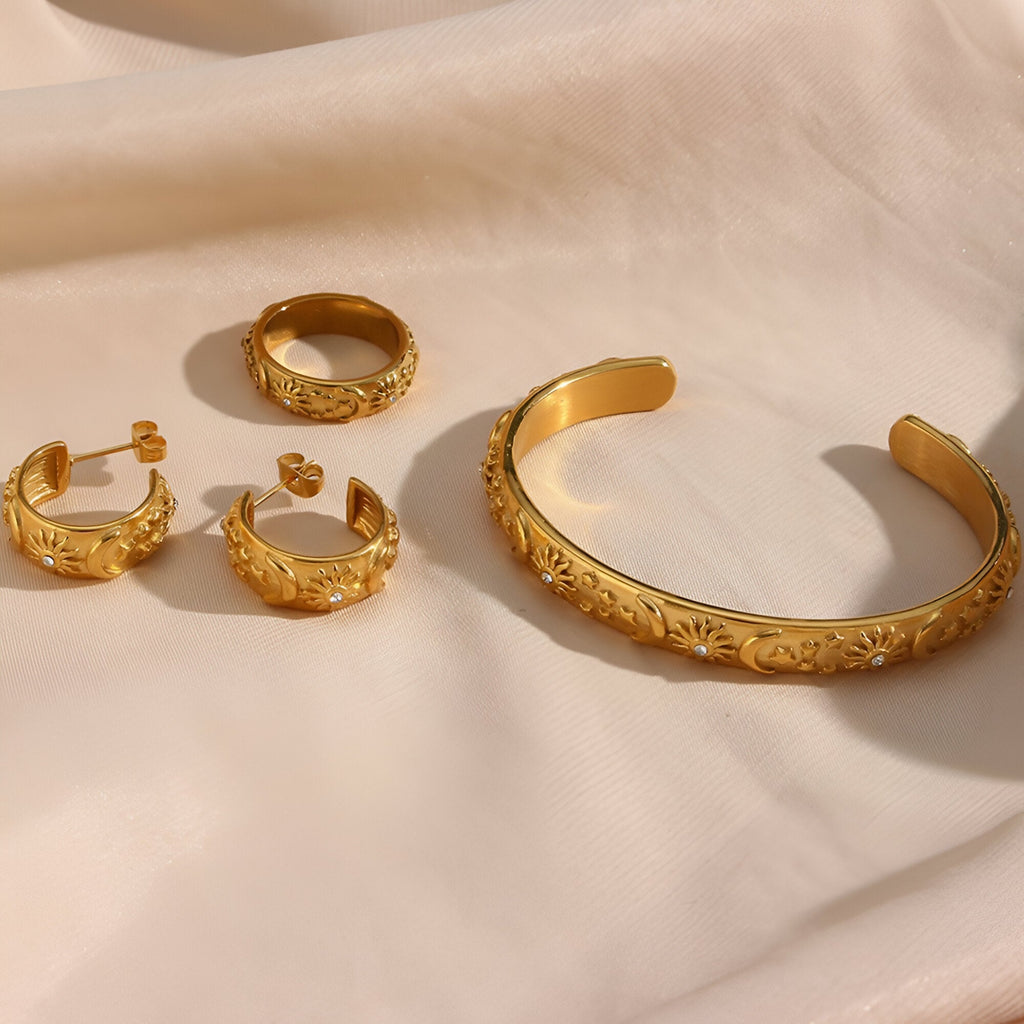 Bracelet jonc or en acier inoxydable avec gravures d'étoiles et boucles d'oreilles assorties designs célestes.