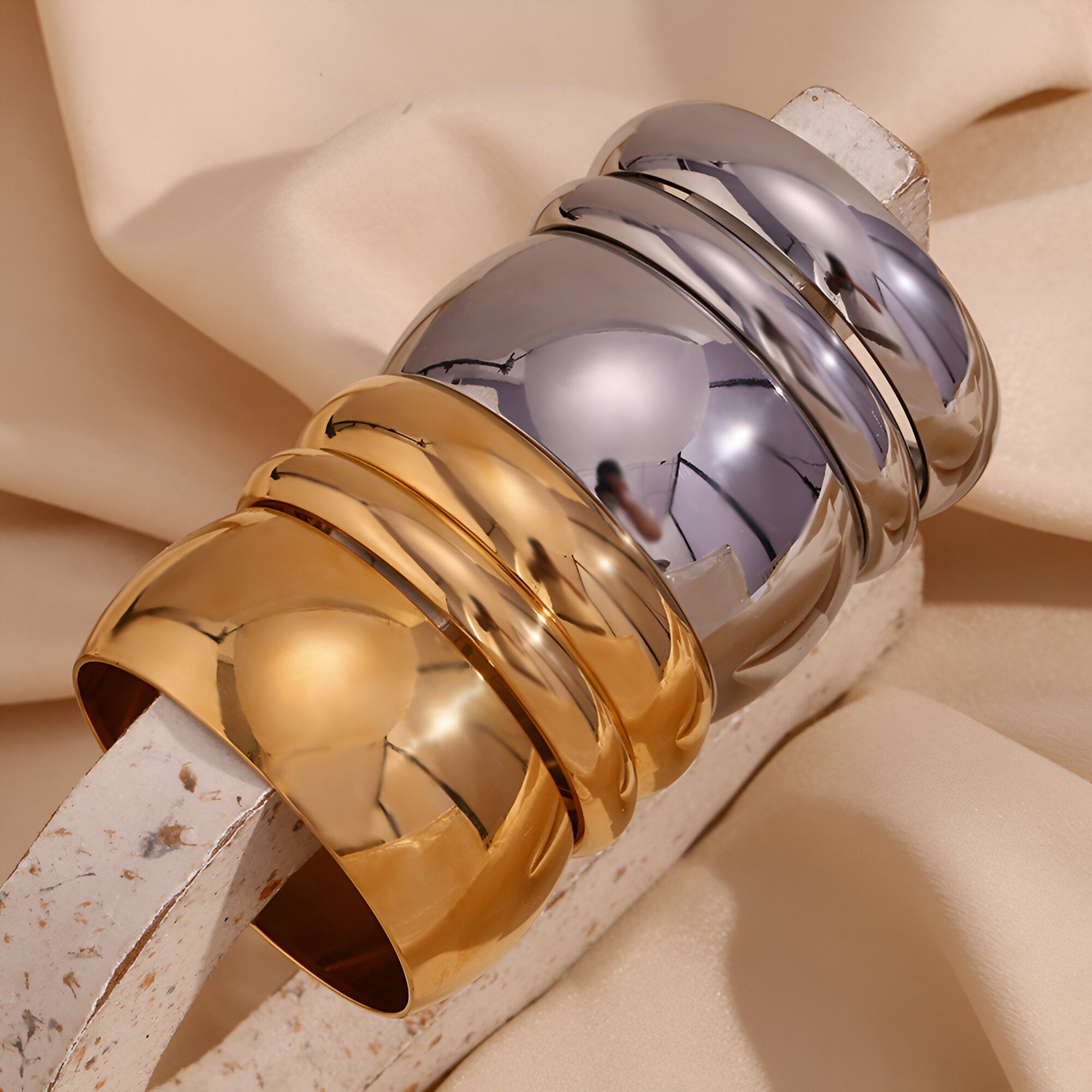 Bracelet jonc épuré en acier inoxydable, finition or brillant et argent lisse.