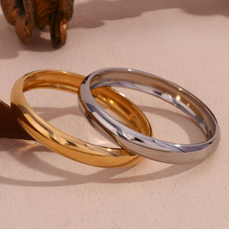 Bracelet jonc épuré en acier inoxydable, finition or brillant et argent lisse, design minimaliste pour femme.