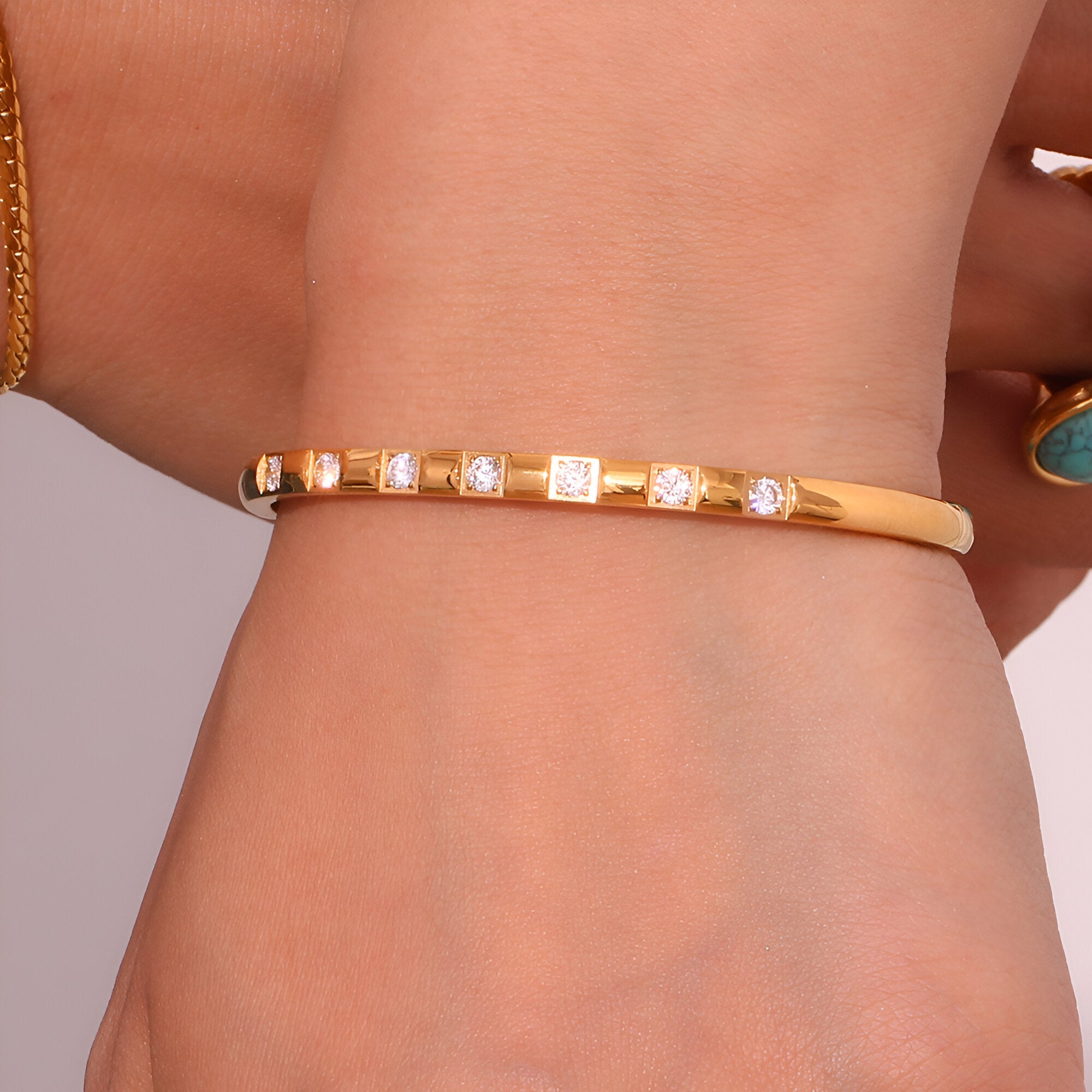 Bracelet jonc fin en acier inoxydable doré avec éclats carrés scintillants, style élégant féminin.