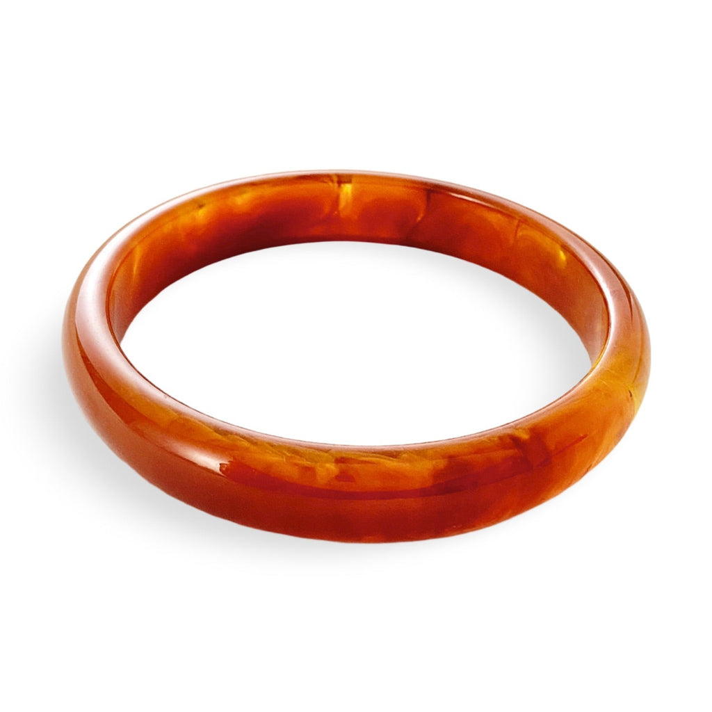 Bracelet jonc en acrylique orange marbré au fini brillant, style épuré et élégant.