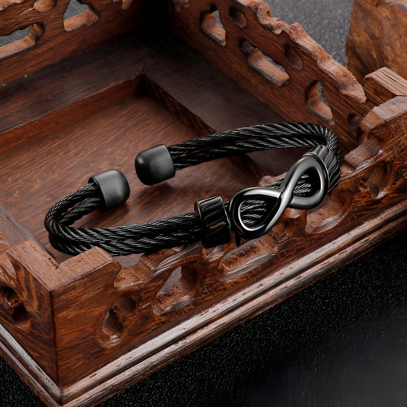 Bracelet jonc noir en acier inoxydable avec motif infini brillant et extrémités lisses.