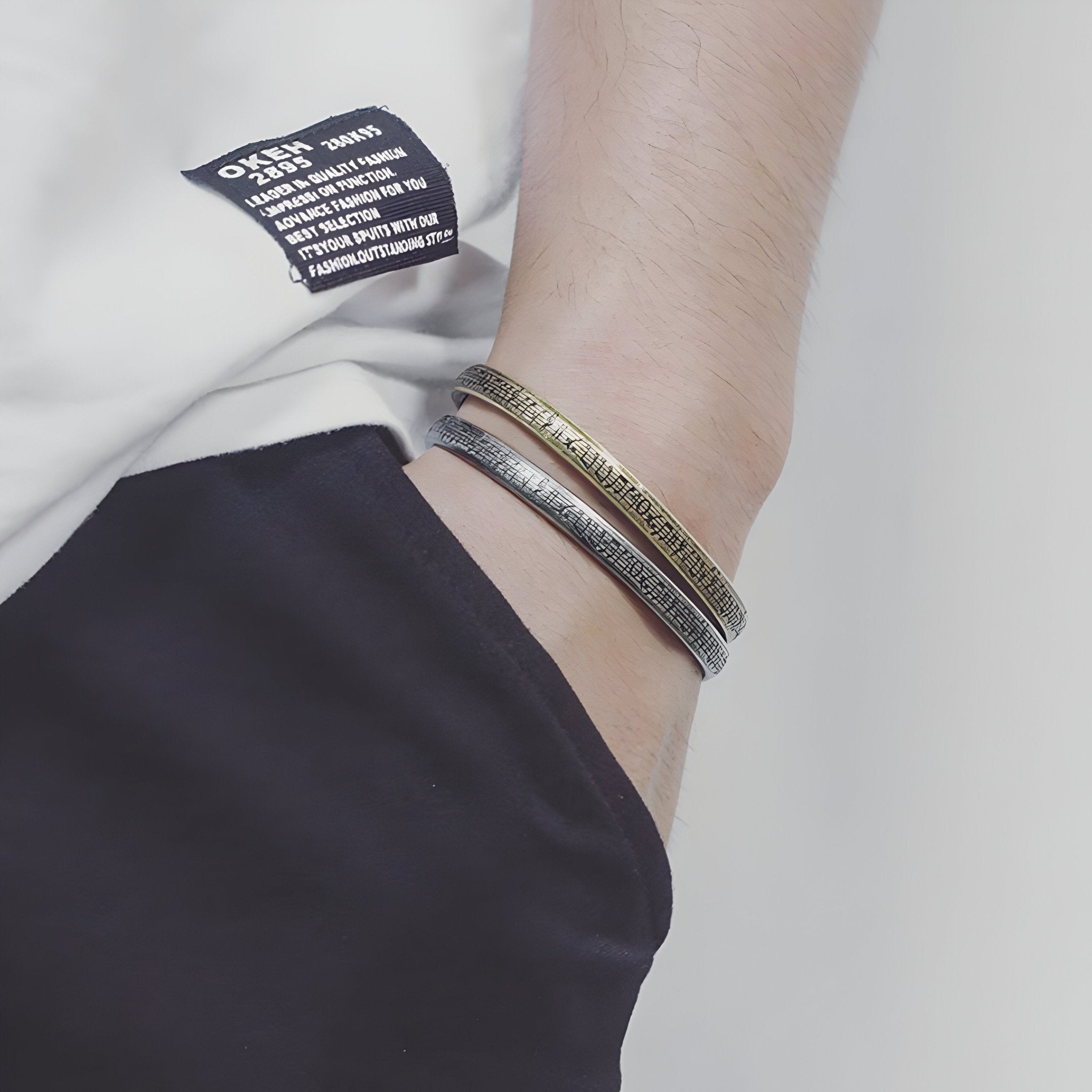 Bracelet jonc en acier inoxydable argenté avec gravures de notes de musique, style mixte, porté au poignet.