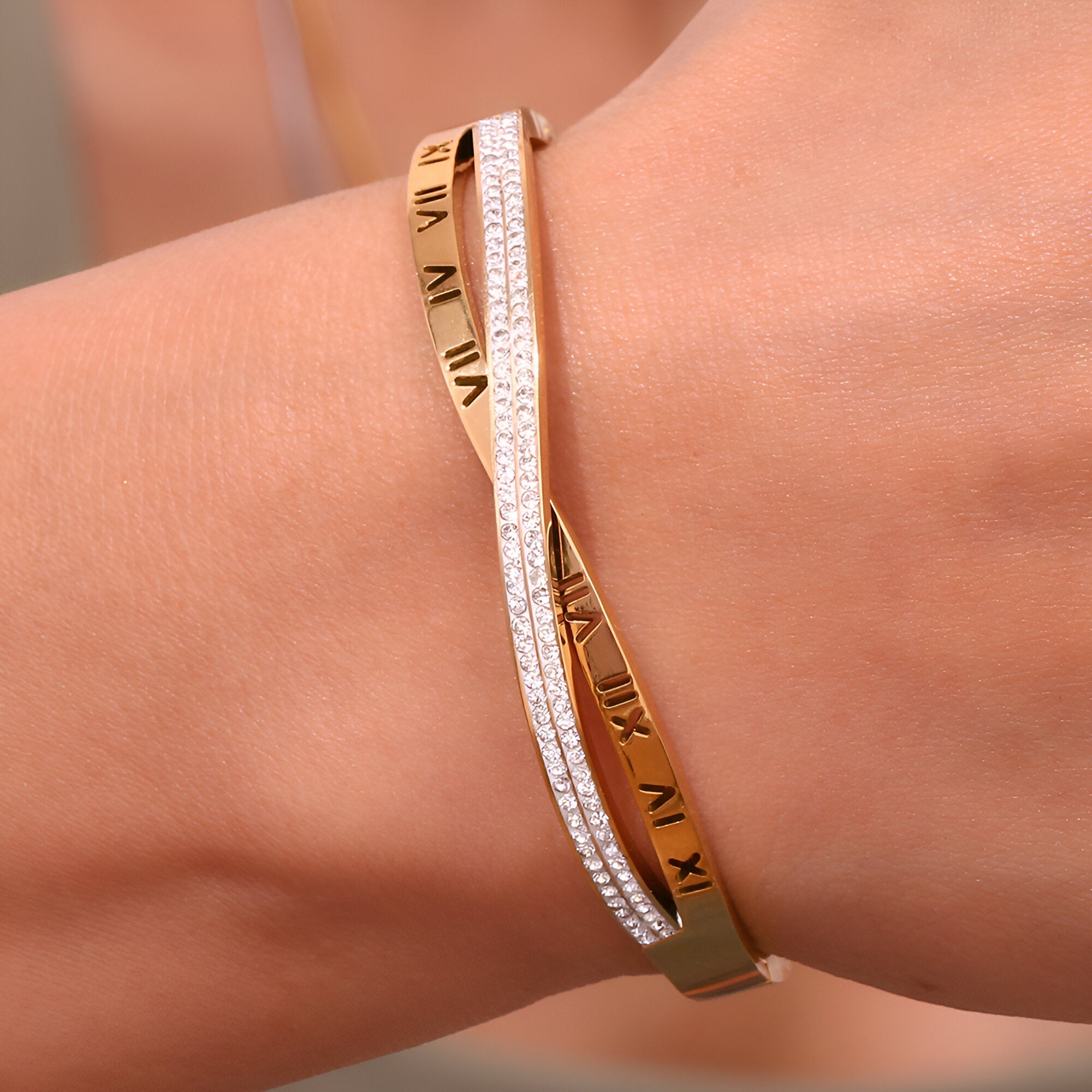 Bracelet jonc en acier doré 18 carats avec inscription chiffres romains et bracelet fin orné de petites pierres scintillantes.