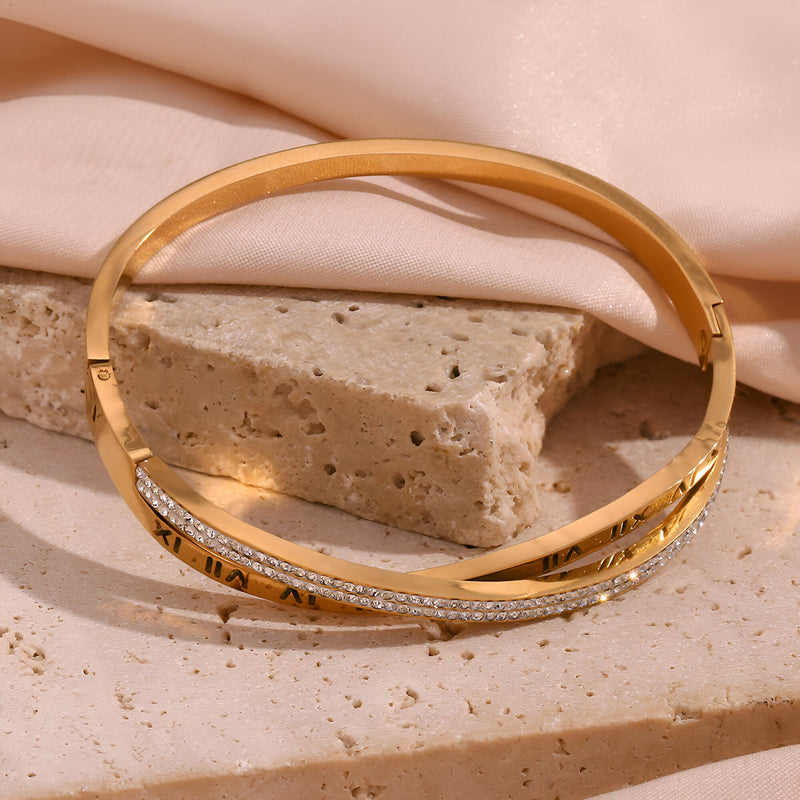 Bracelet jonc en acier inoxydable doré 18 carats avec gravure chiffres romains et détail strassé.