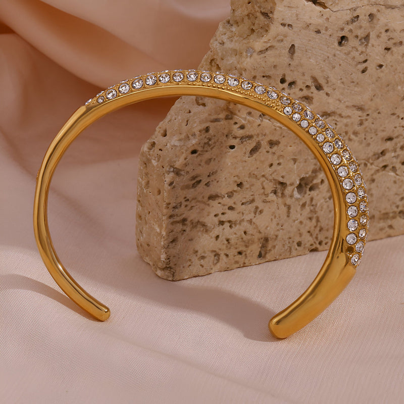 Bracelet jonc doré 18 carats avec rangée de zircons brillants, design élégant et minimaliste.