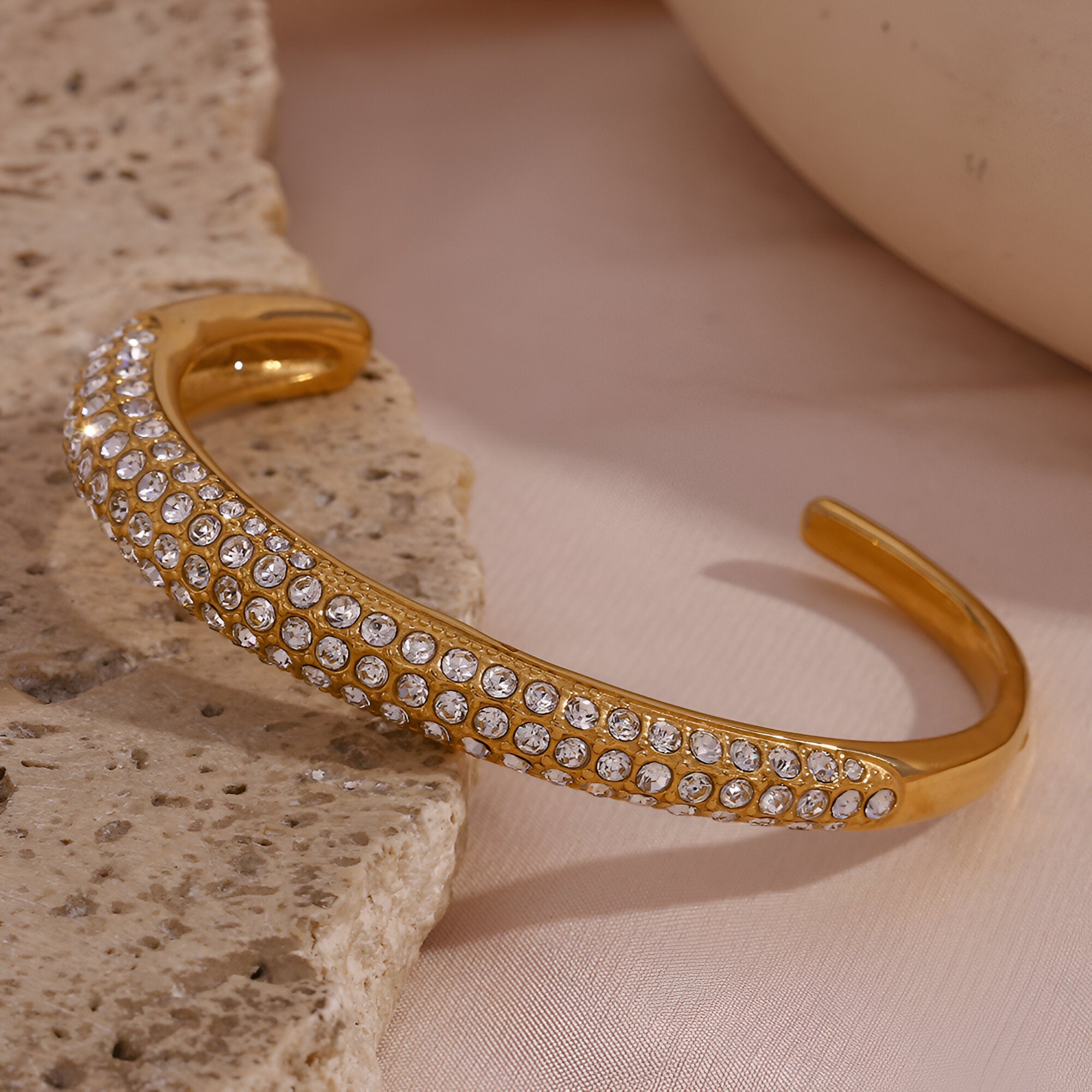Bracelet jonc en acier plaqué or 18 carats orné de trois rangées de zircons scintillants.