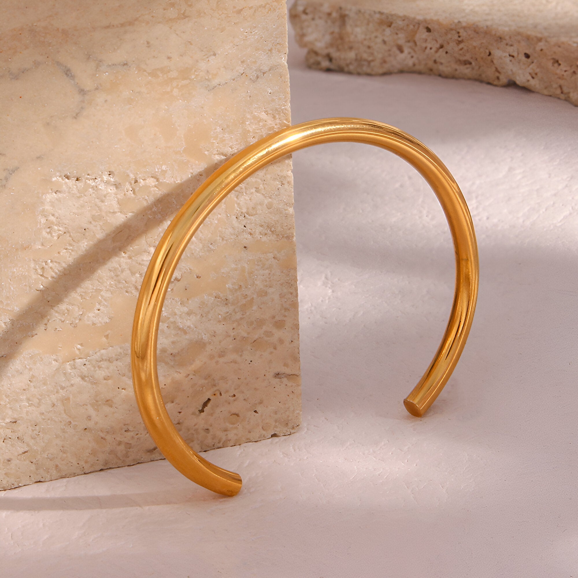 Bracelet jonc ouvert en acier inoxydable doré, finition lisse et brillante, style épuré féminin.