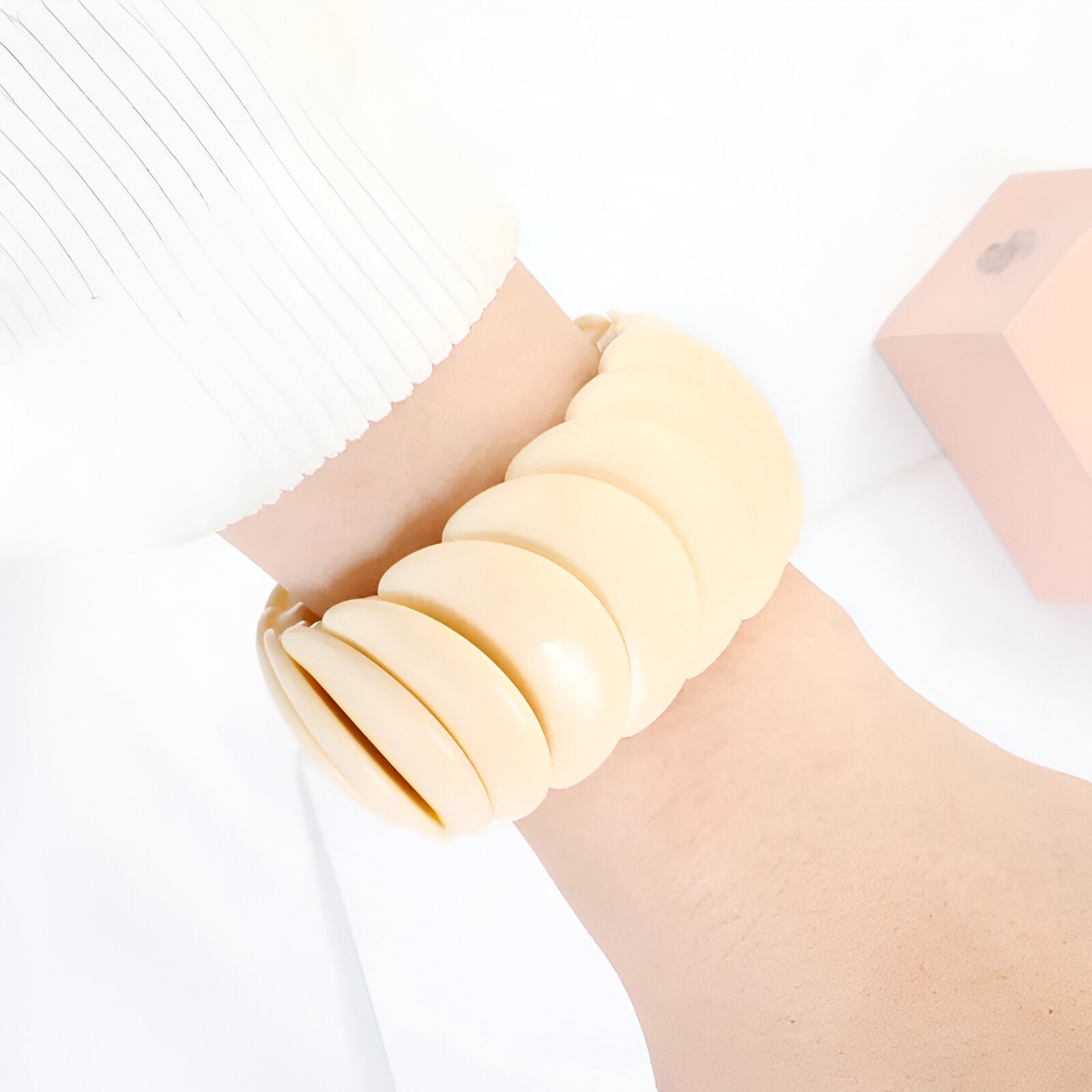 Bracelet jonc épais beige en acrylique avec plusieurs anneaux lisses et larges.