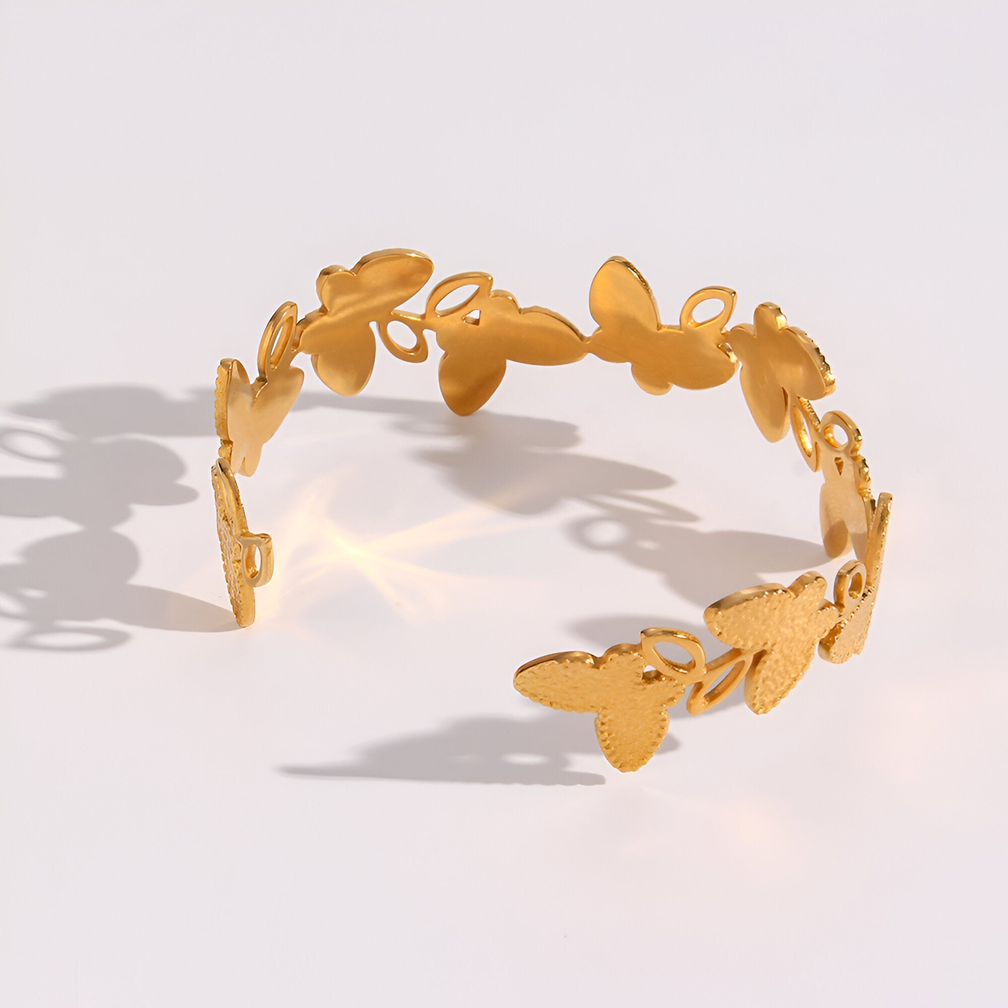 Bracelet jonc en acier inoxydable doré avec motif floral découpé délicat.
