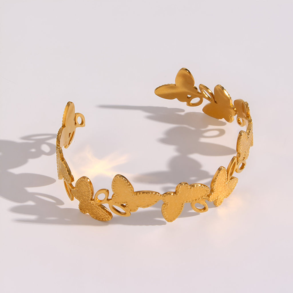 Bracelet jonc doré en acier inoxydable avec motifs floraux ajourés élégants.