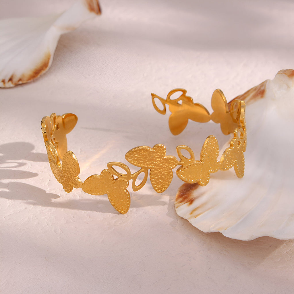 Bracelet jonc en acier inoxydable doré orné de fleurs découpées délicates et texturées.