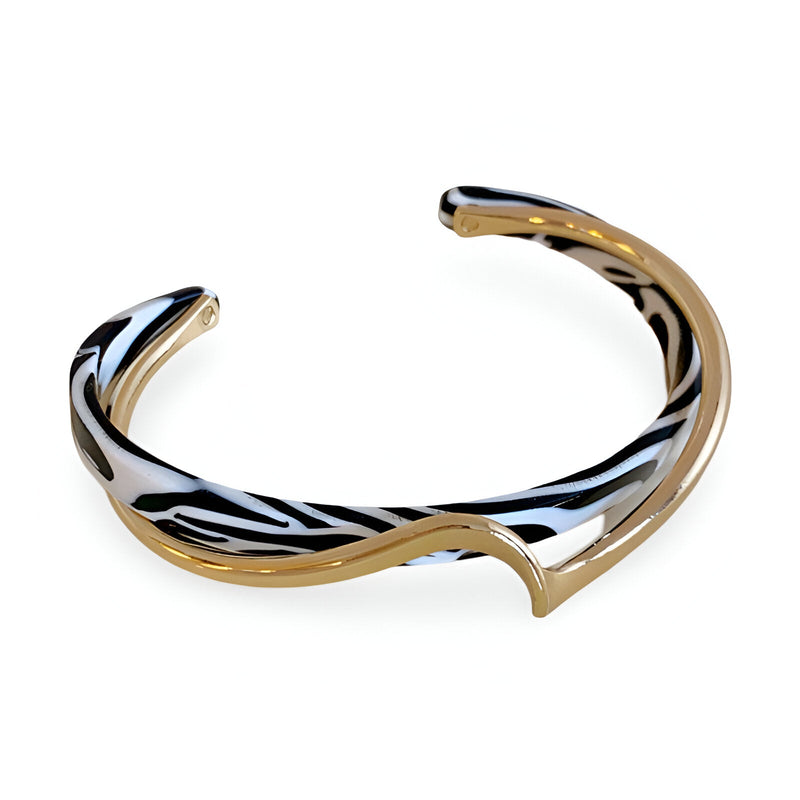 Bracelet jonc ouvert en acrylique blanc à motifs léopard noirs et détails en métal doré brillant.