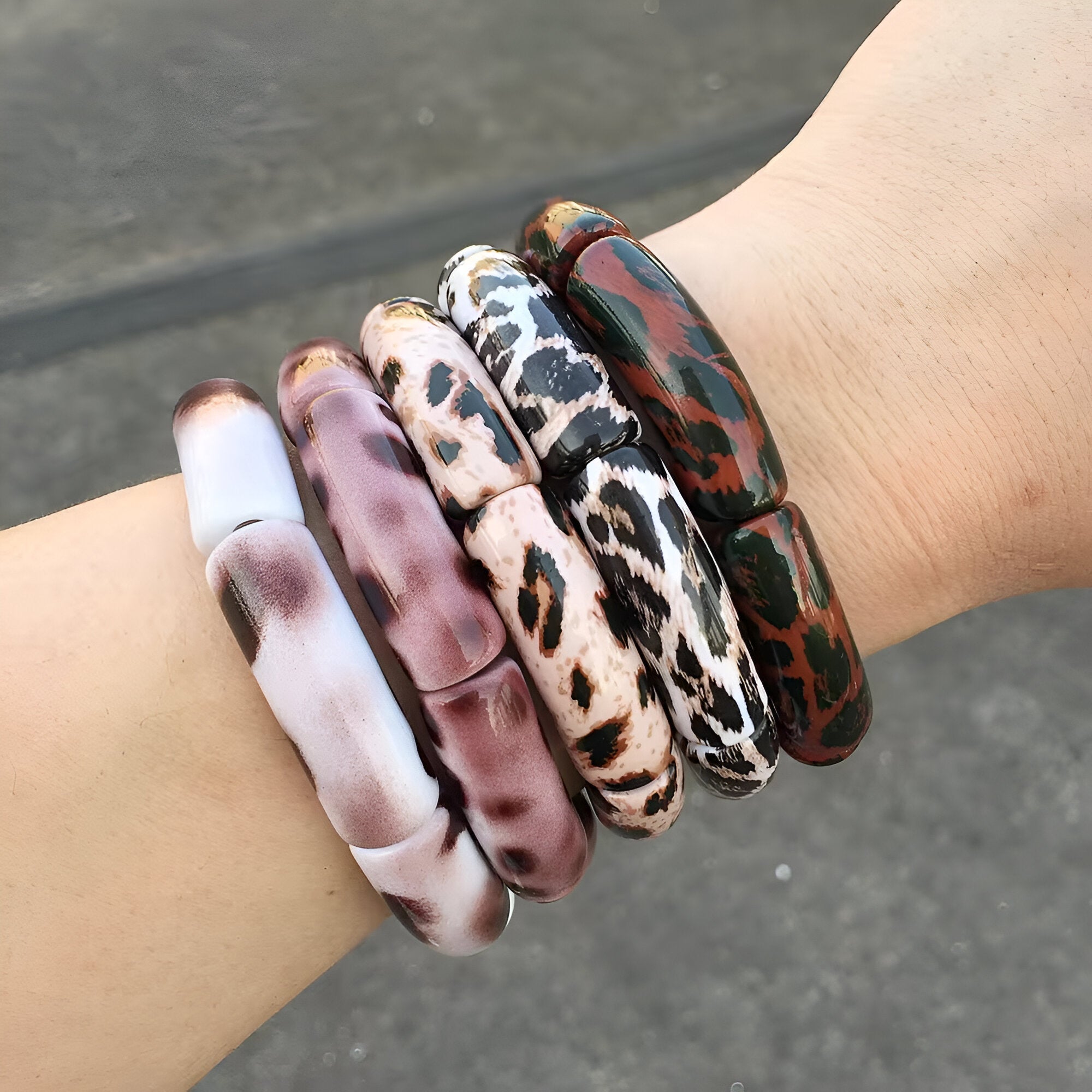 Bracelets joncs larges en acrylique avec motif léopard multicolore porté sur le poignet.