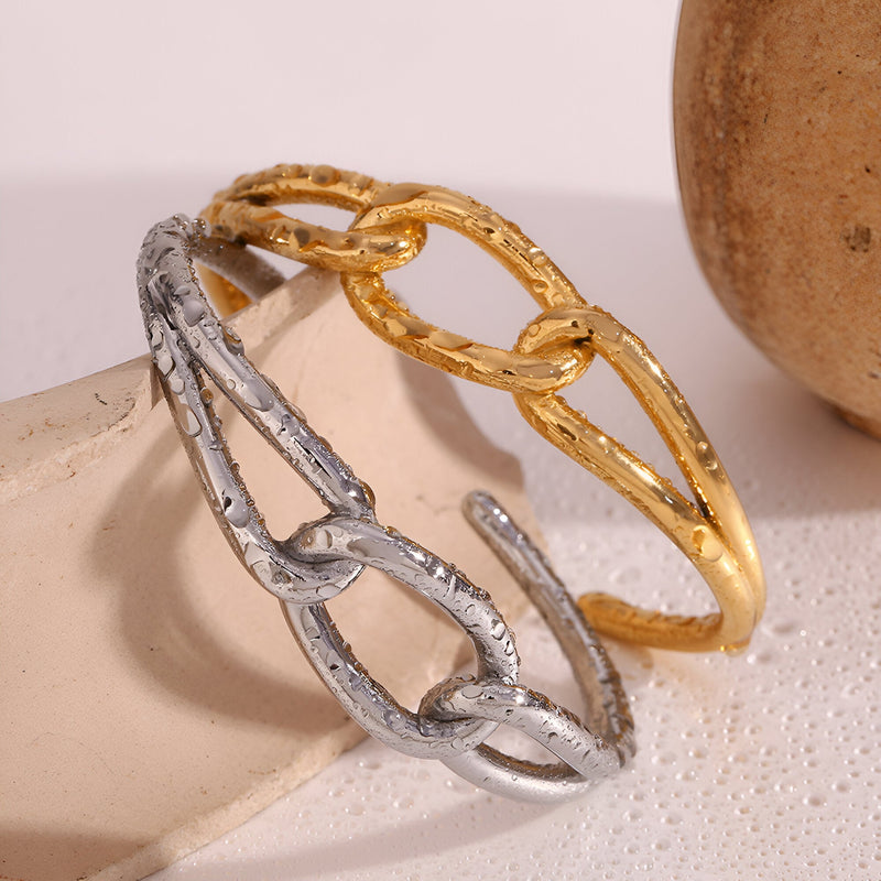 Paire de bracelets joncs Callia en acier inoxydable, un en or texturé, l'autre en argent texturé, avec maillon central.