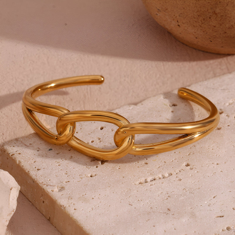 Bracelet jonc doré en acier inoxydable avec un maillon central unique et design épuré.