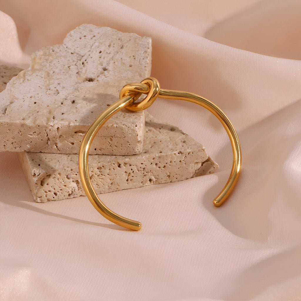 Bracelet jonc ouvert doré en acier inoxydable avec nœud infini élégant.