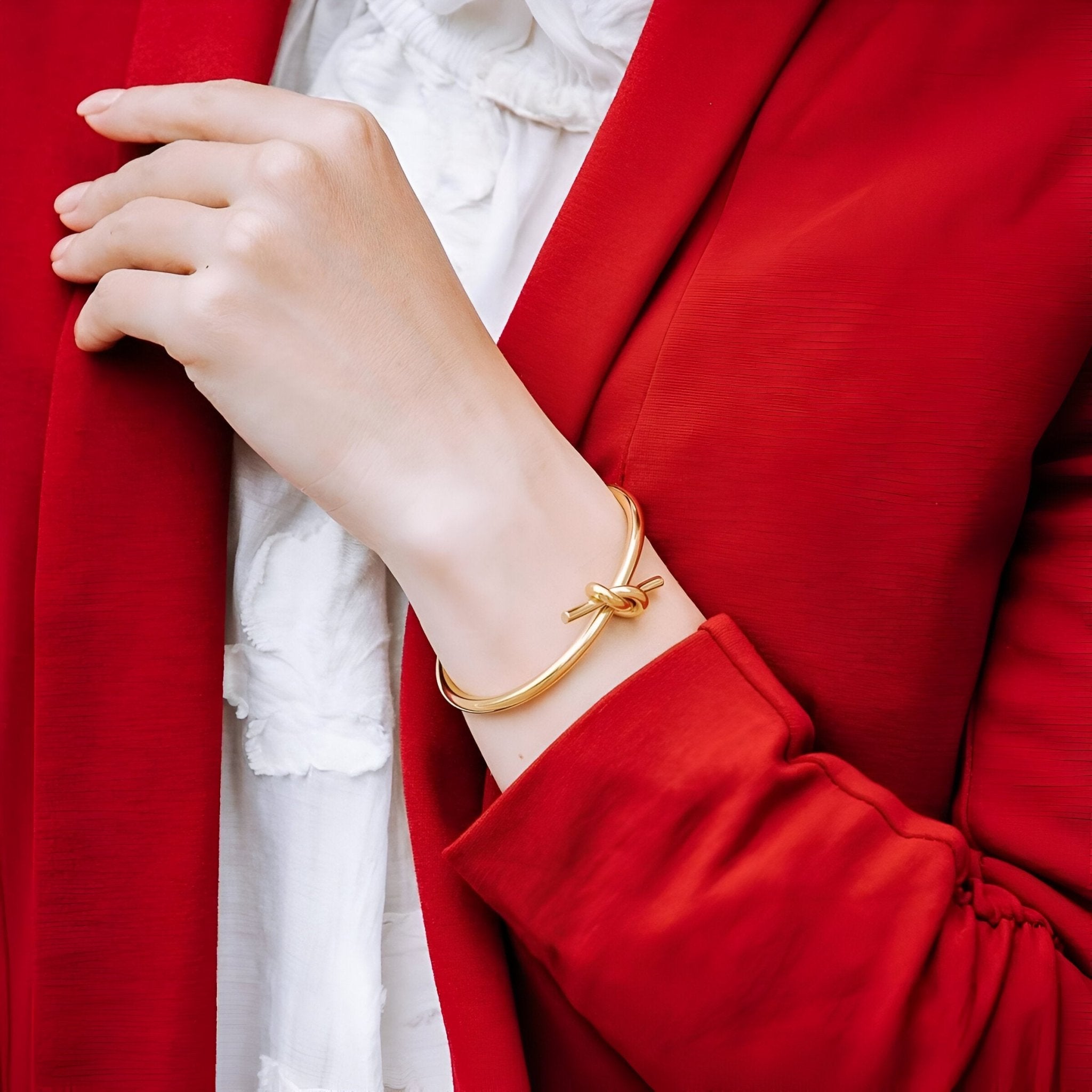 Bracelet jonc en acier inoxydable or avec nœud élégant porté sur poignet féminin.