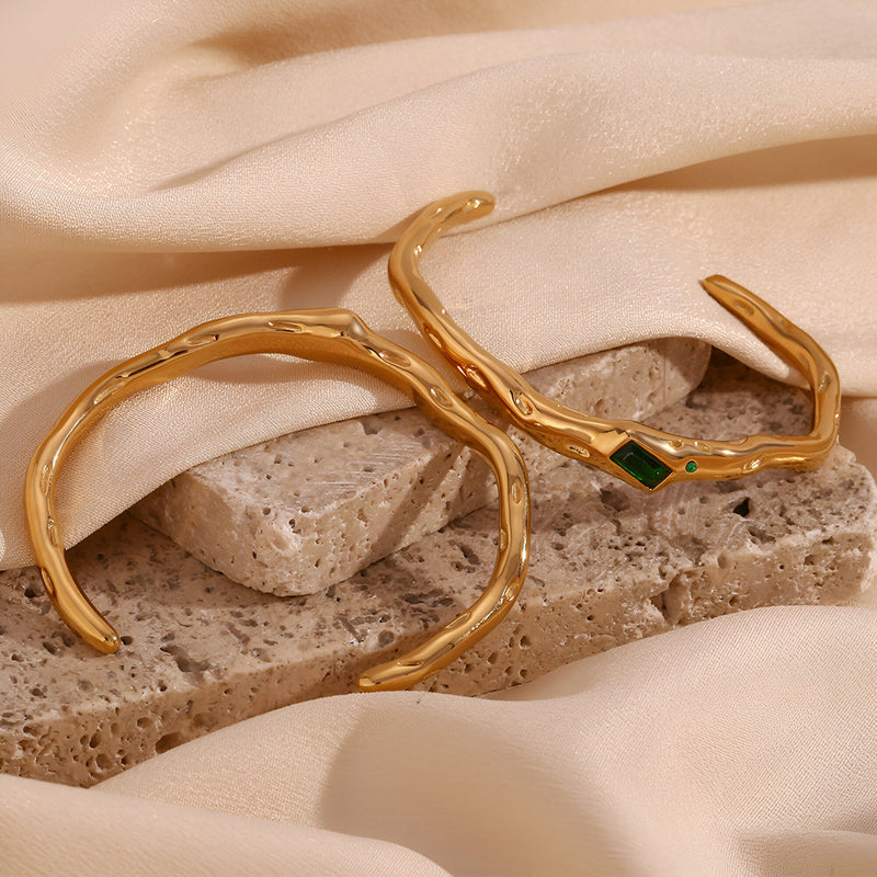 Bracelet jonc ondulé en acier inoxydable doré avec pierre verte rectangulaire brillante.