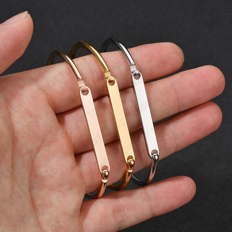 Trois bracelets joncs personnalisés en acier inoxydable or rosé, or jaune et argent, modèle Garcia, portés sur la main.