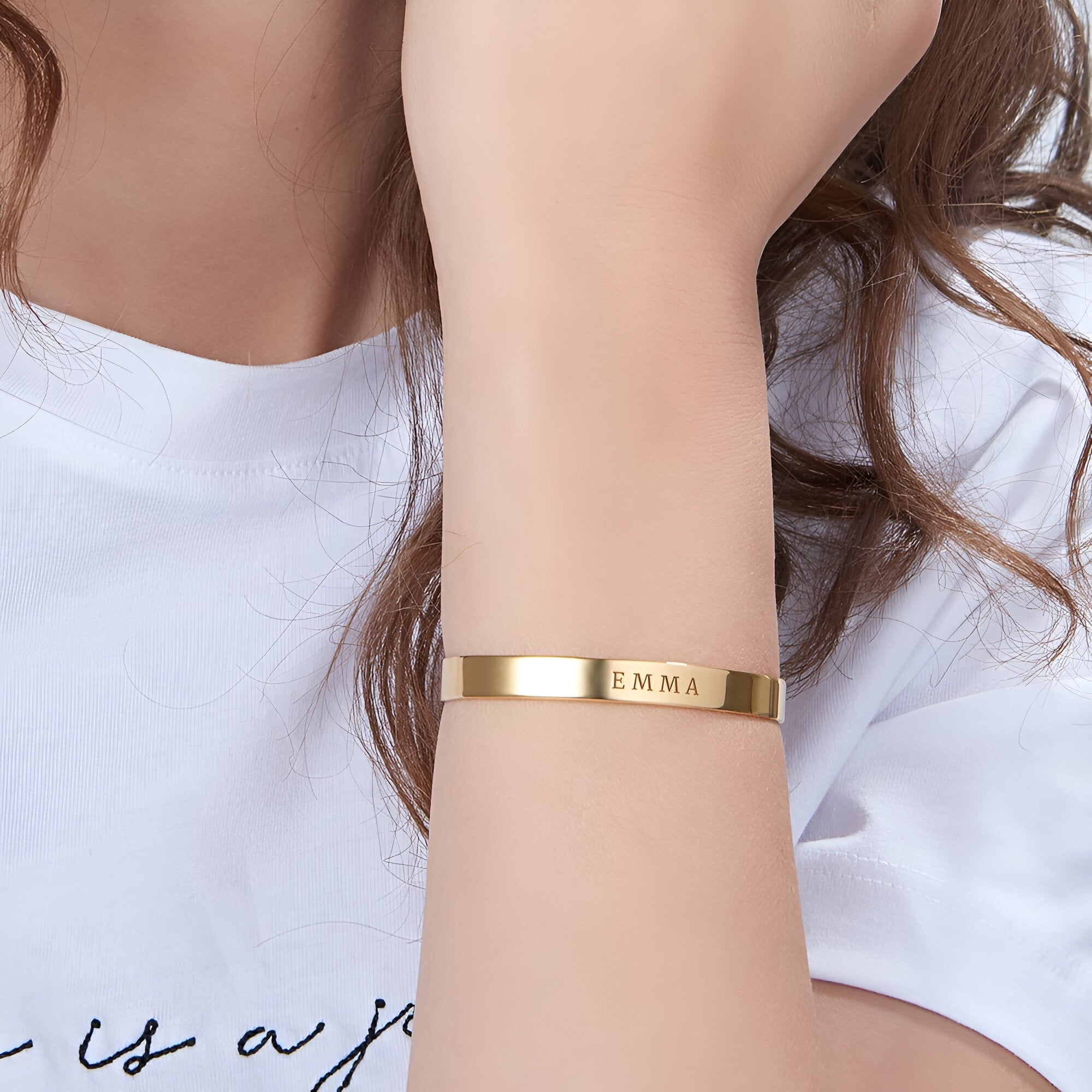 Bracelet jonc en or rose personnalisé avec lettres gravées porté au poignet.