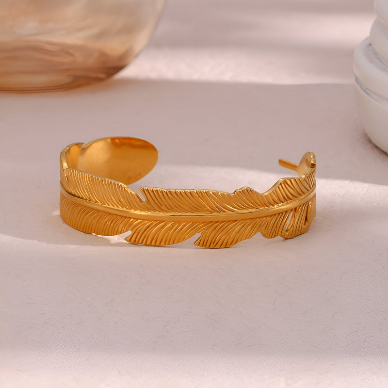 Bracelet jonc doré en acier inoxydable en forme de plume délicate et texturée.