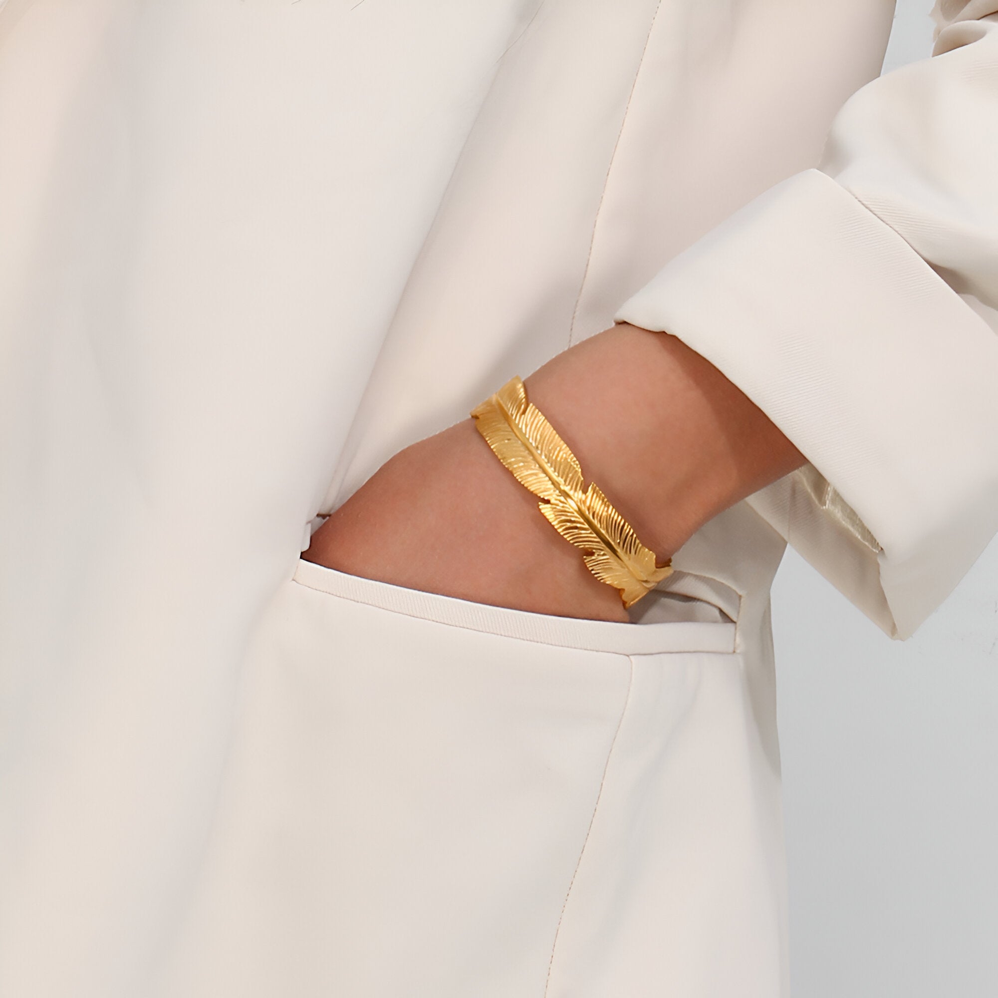 Bracelet jonc en acier inoxydable doré avec design plume texturée, style élégant pour femme.