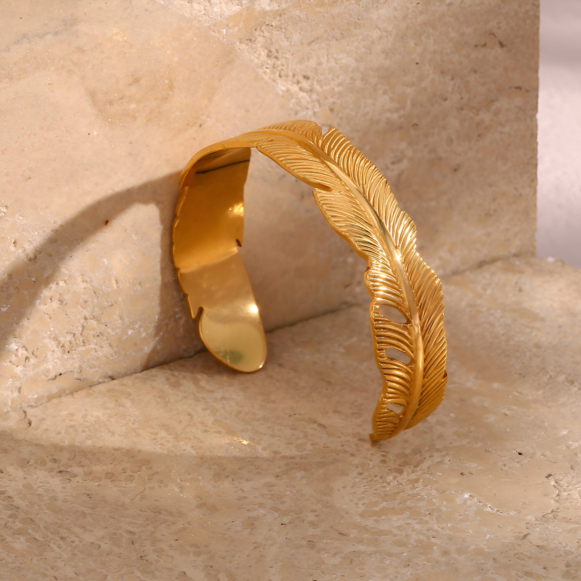 Bracelet jonc doré en acier inoxydable avec motif plume finement gravé.