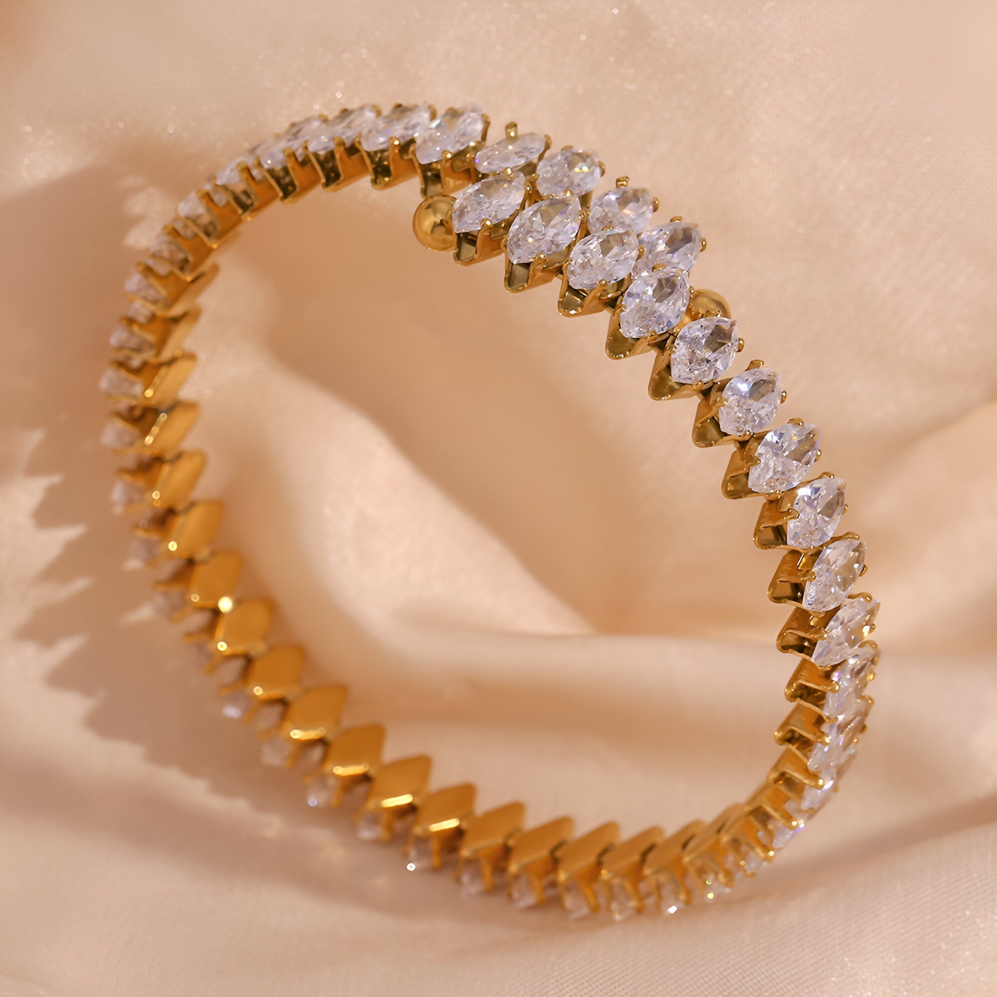 Bracelet jonc or en acier inoxydable orné de pierres scintillantes en forme de goutte.