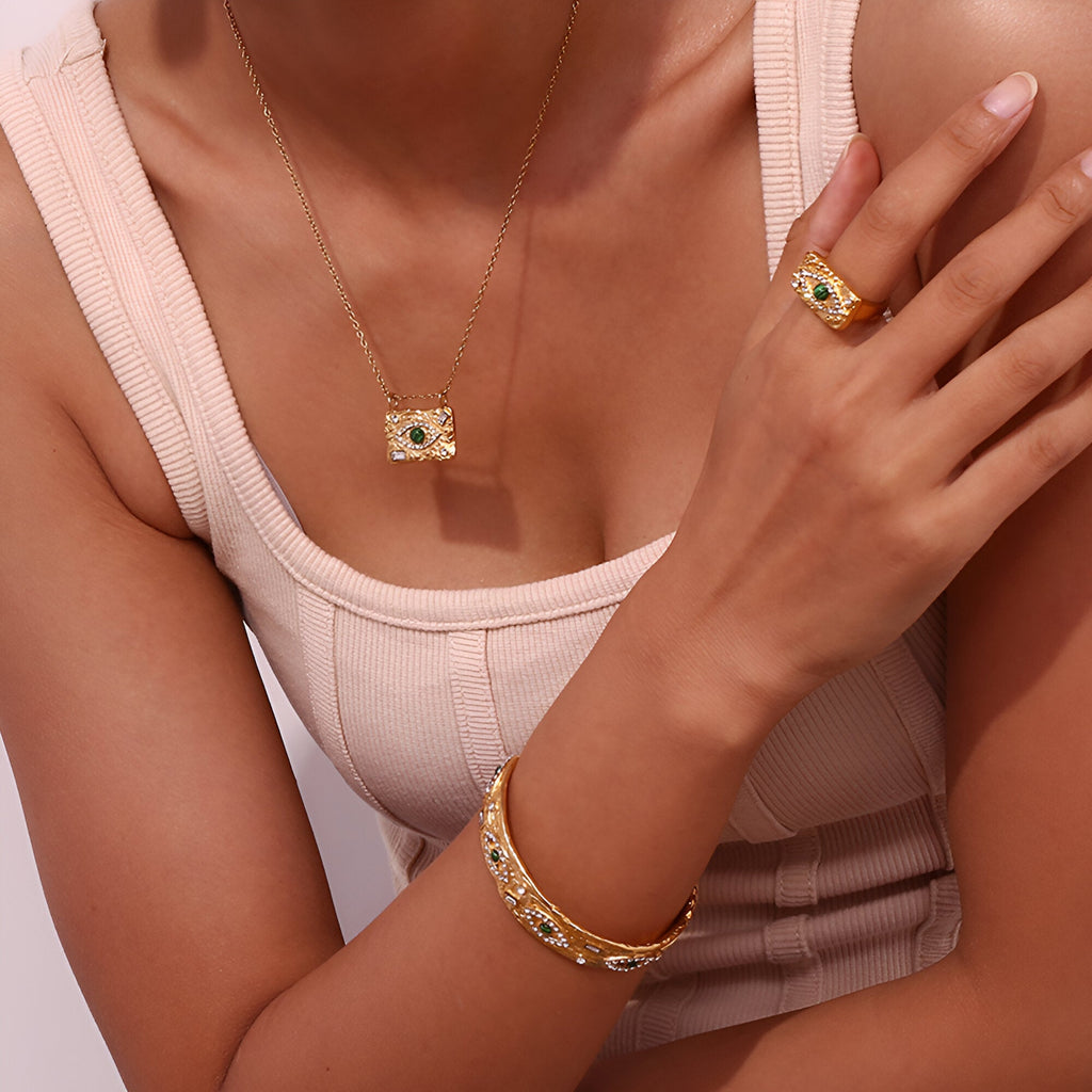 Bracelet jonc en acier inoxydable doré avec motifs gravés porté au poignet, style élégant et protecteur.
