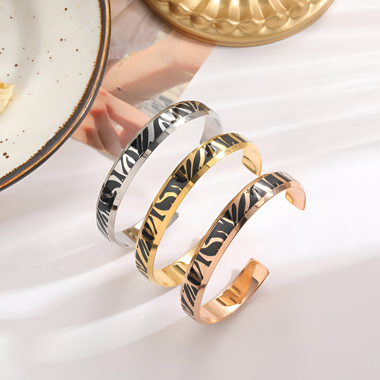 Trois bracelets joncs en titane, motifs tigrés, finition argent, or et or rosé, pour femme.
