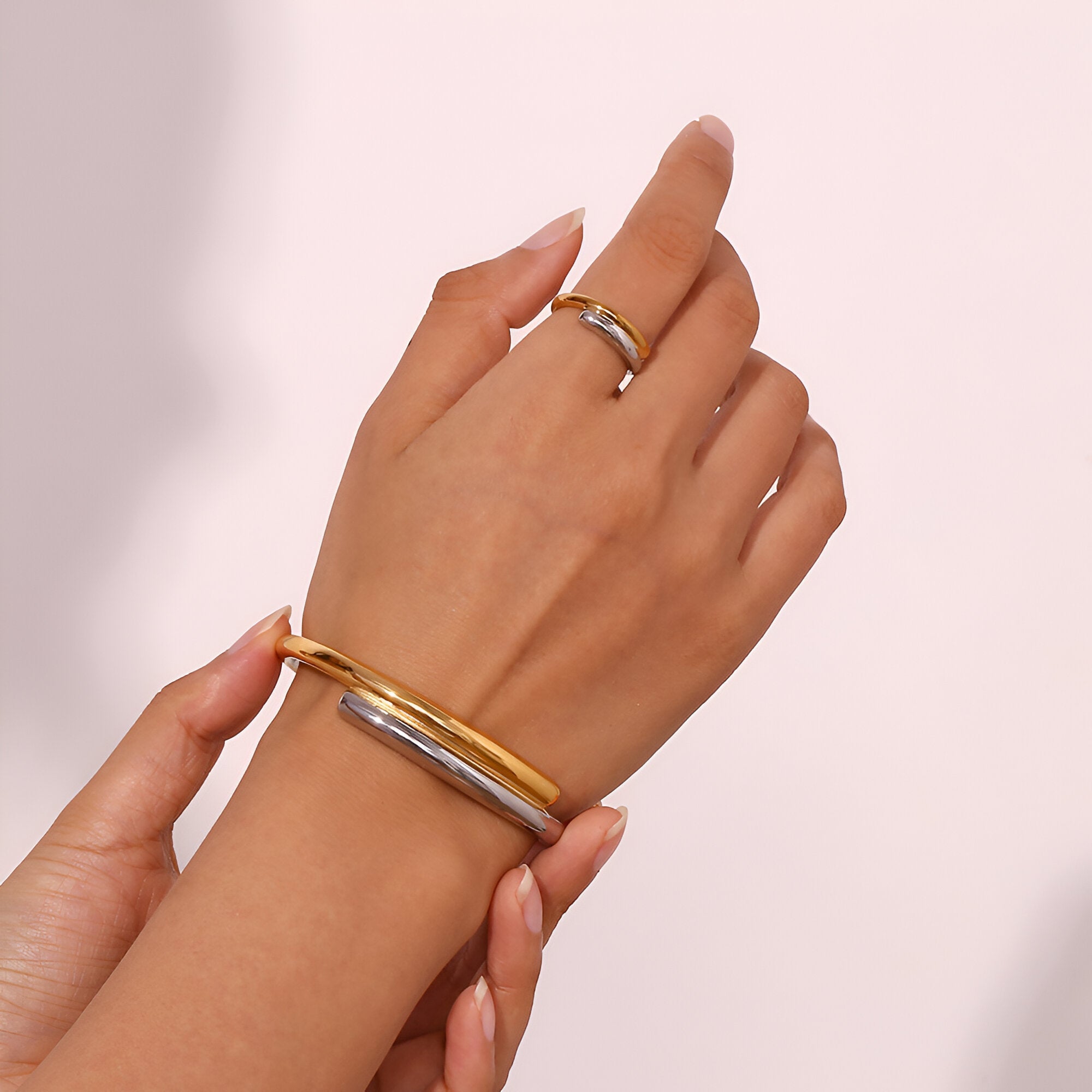 Bracelet jonc en acier inoxydable bicolore or et argent, design lisse et élégant, porté au poignet.