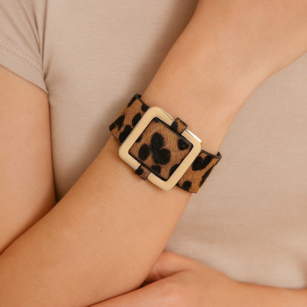 Bracelet large en tissu léopard marron avec boucle carrée beige porté au poignet féminin.