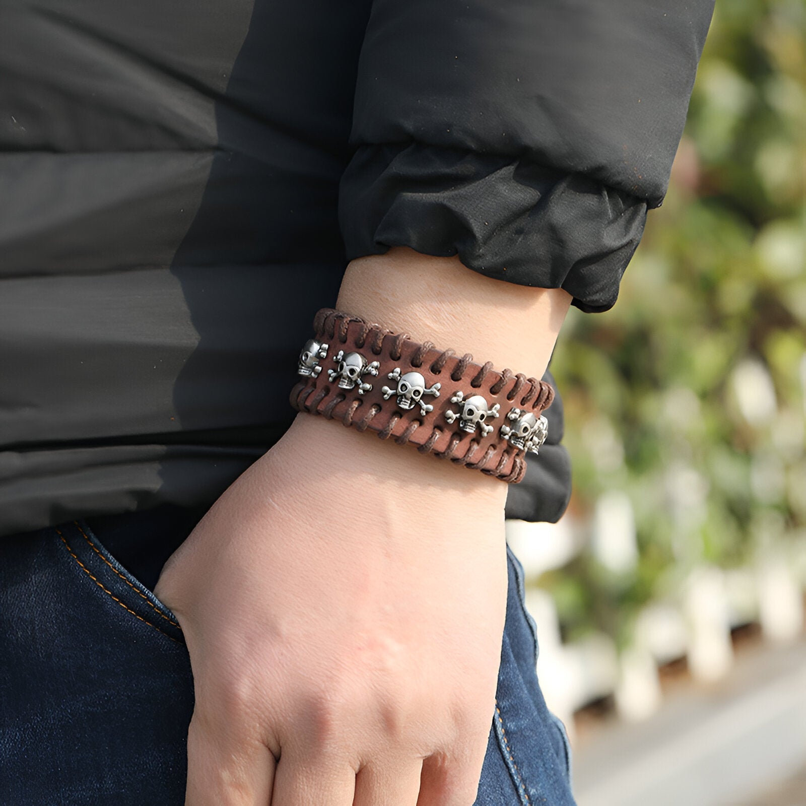 Bracelet large en cuir marron orné de têtes de mort métalliques argentées pour homme.