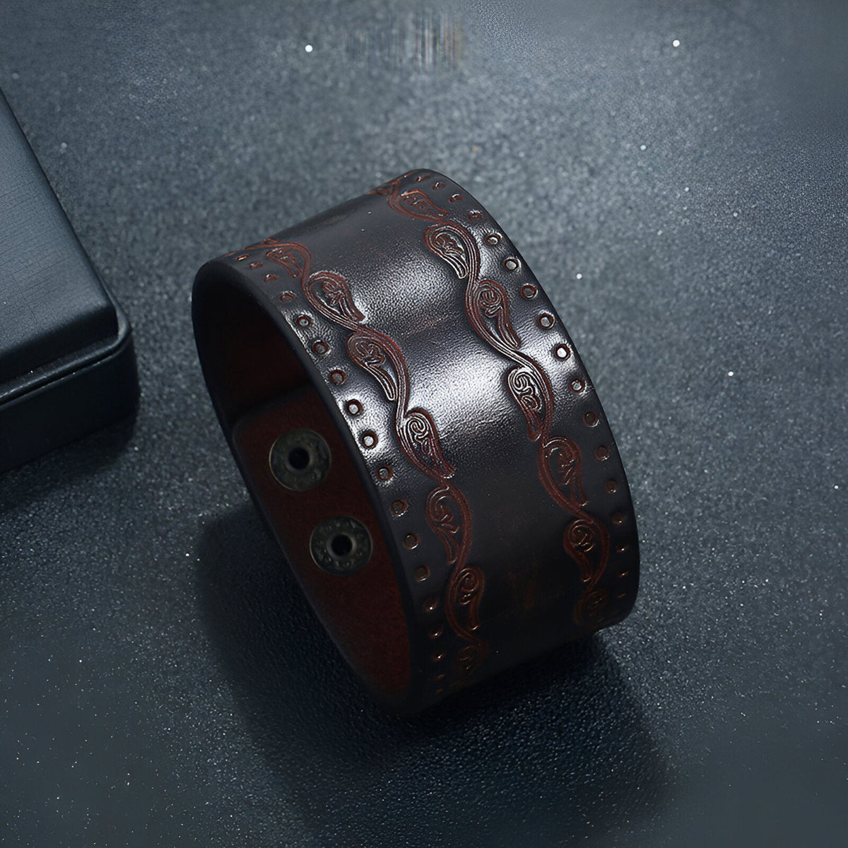 Bracelet large en cuir café avec motifs western embossés et fermeture à boutons pression.