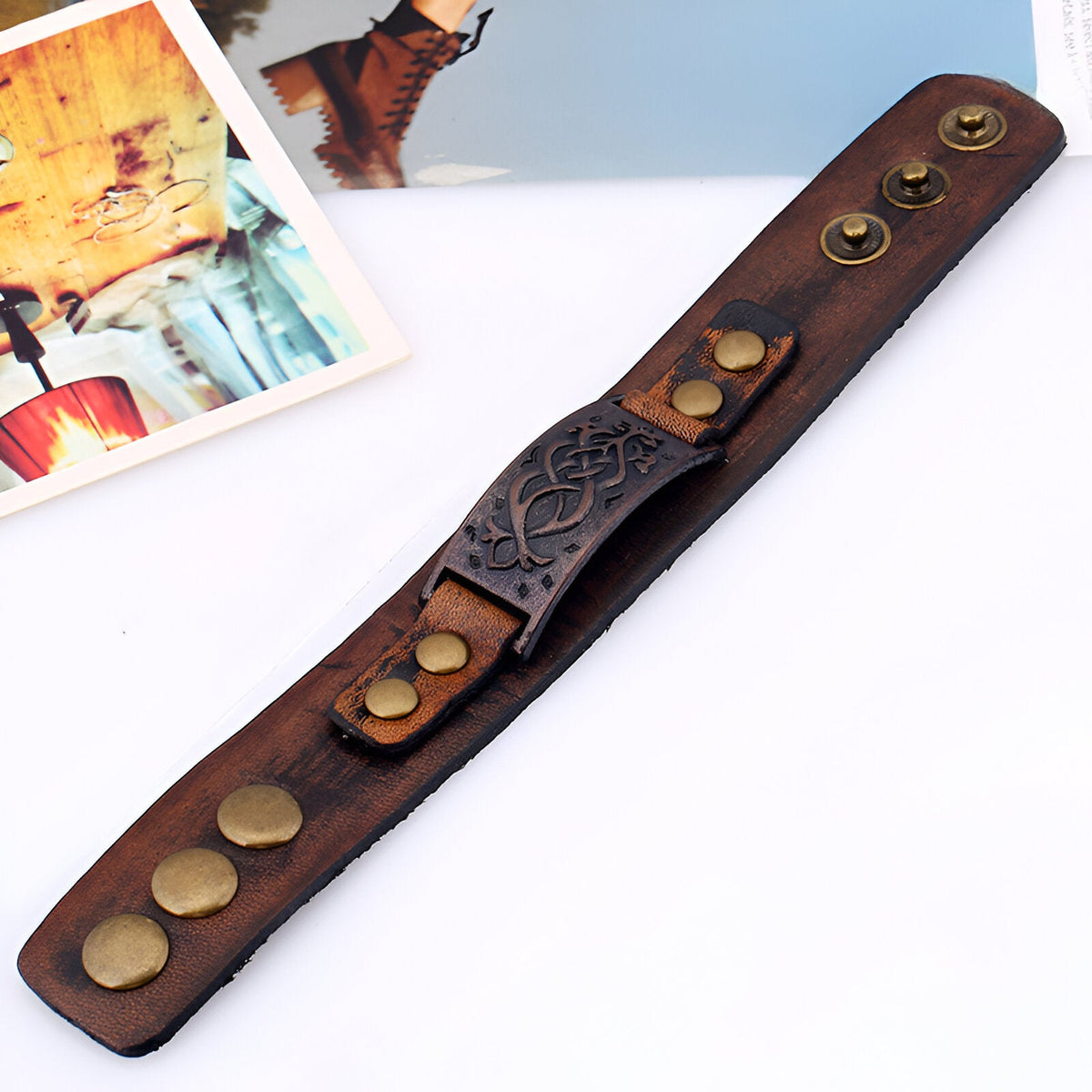 Bracelet large en cuir marron avec motif floral gravé et boutons-pression en métal vieilli.