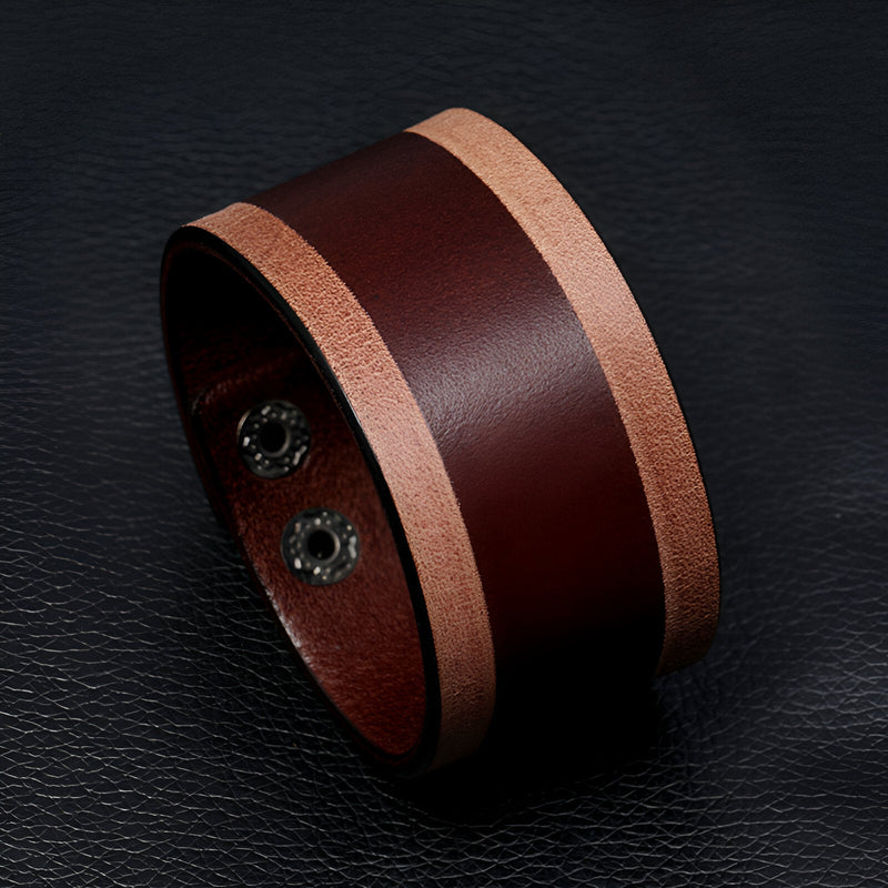 Bracelet large en cuir marron avec bordures naturelles et fermeture à boutons pression en métal.