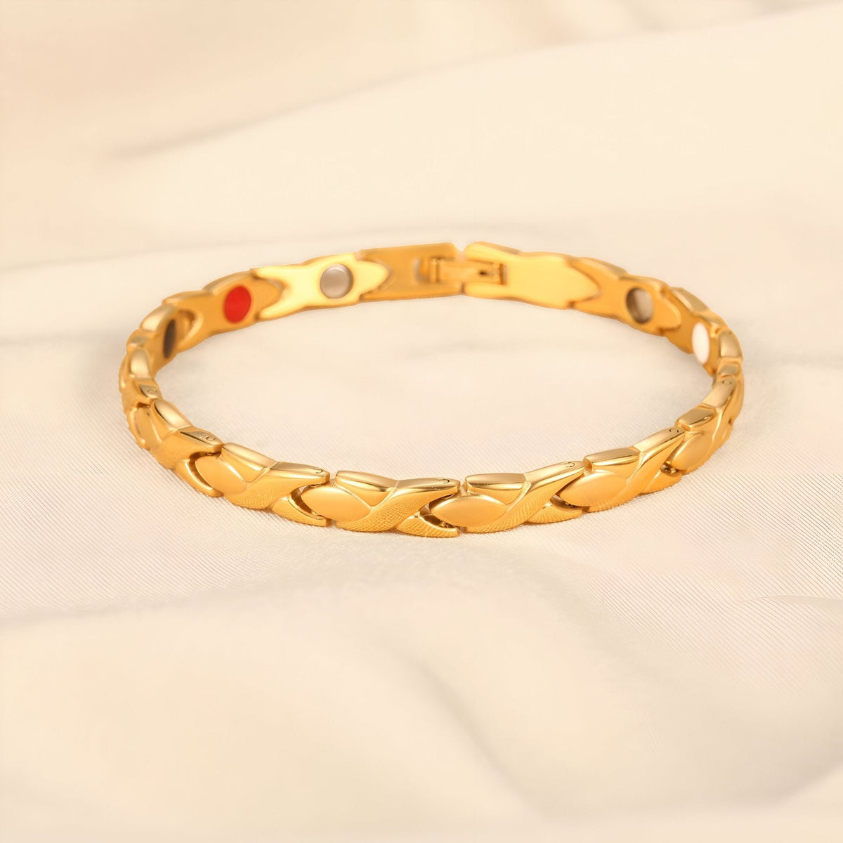 Bracelet magnétique en titane doré avec maillons incurvés et pastilles colorées au revers.