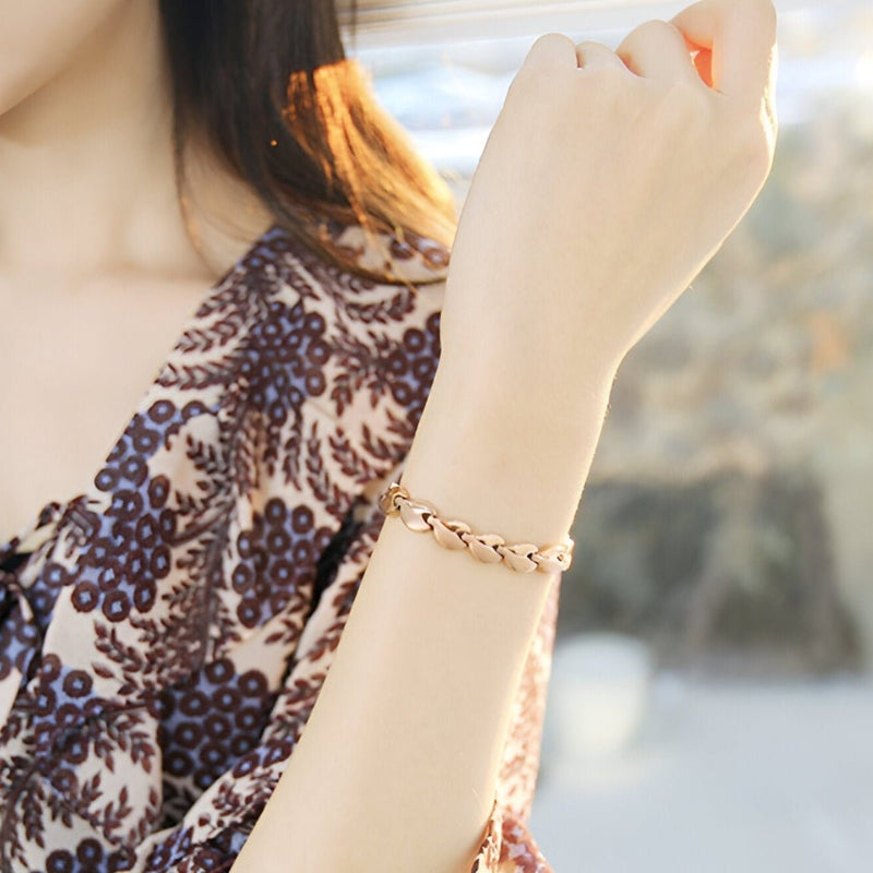 Bracelet magnétique en or rosé à maillons larges porté au poignet féminin.