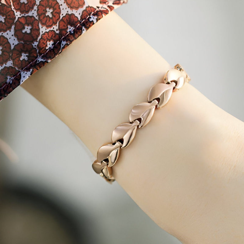 Bracelet magnétique en or rosé avec maillons incurvés élégants porté au poignet féminin.