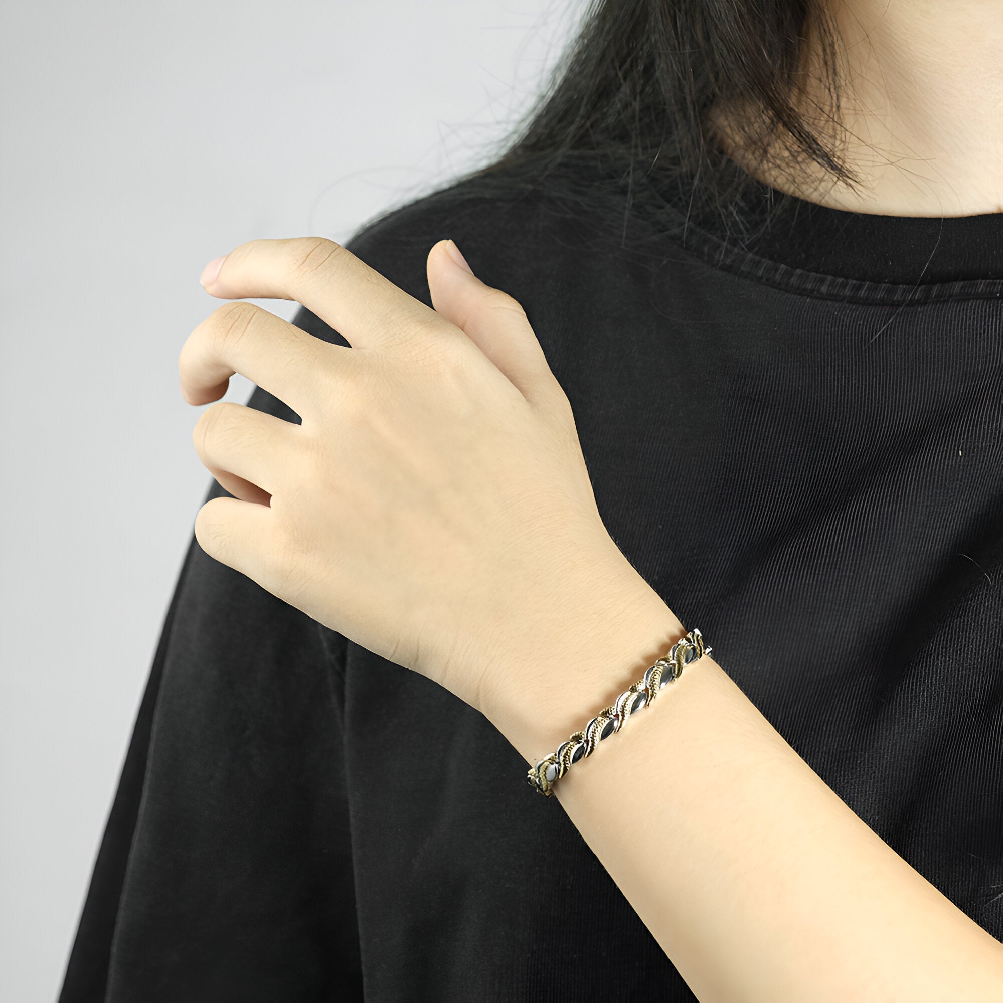 Bracelet magnétique en titane argenté avec maillons larges porté à un poignet féminin.