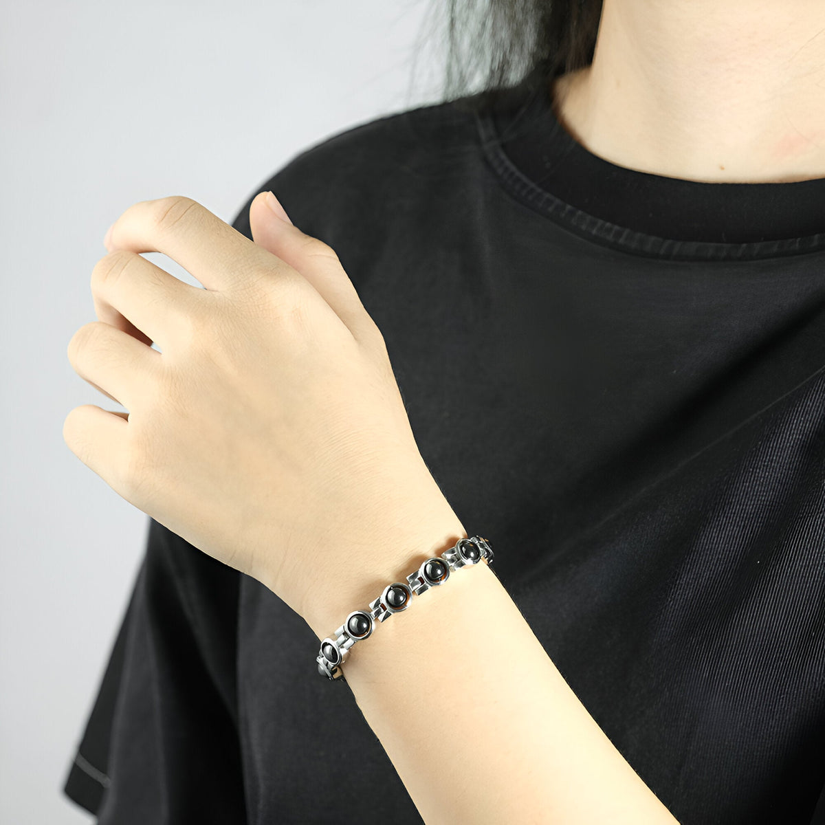 Bracelet magnétique en titane argenté à maillons arrondis porté au poignet féminin.