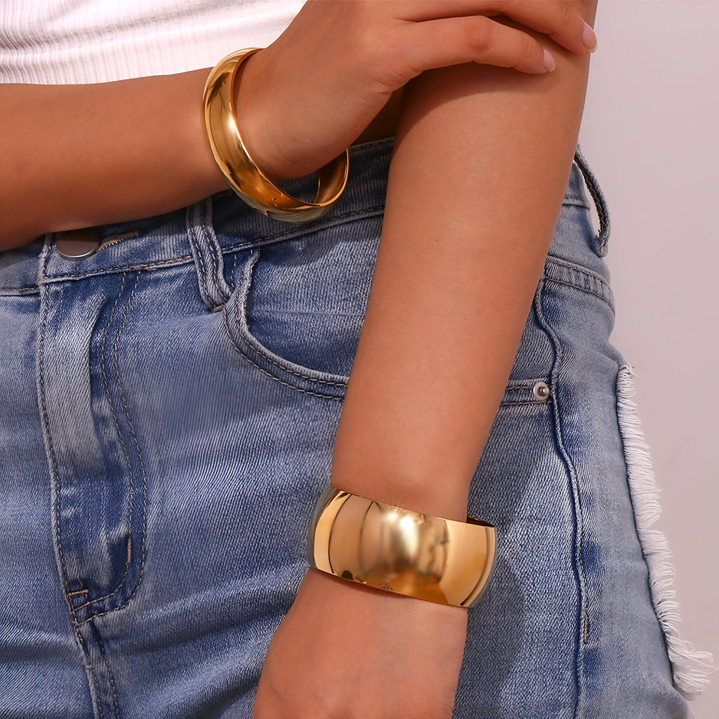 Bracelet manchette large en acier inoxydable doré, finition lisse et brillante, style épuré.
