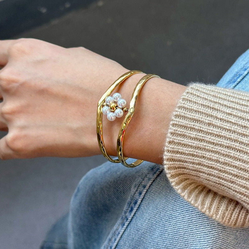 Brazalete dorado tipo manchette, flor de perlas blancas, en acero inoxidable, modelo Nelyra