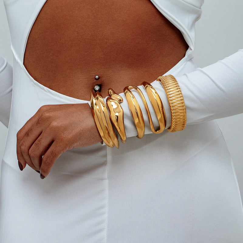 Bracelet manchette doré en acier inoxydable, design texturé avec formes ondulées, style moderne et large.