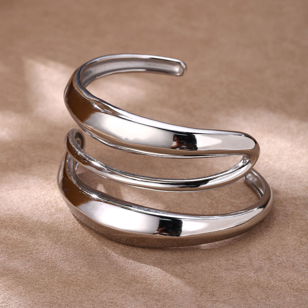 Bracelet manchette en acier inoxydable argenté, design sculpté ondulé et ouvert sur le côté.