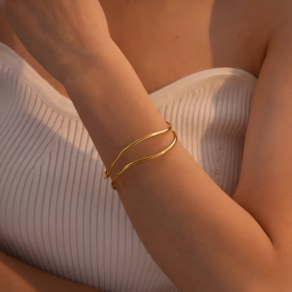 Bracelet manchette Mirabel en titane plaqué or, design fin et contemporain sur peau bronzée.